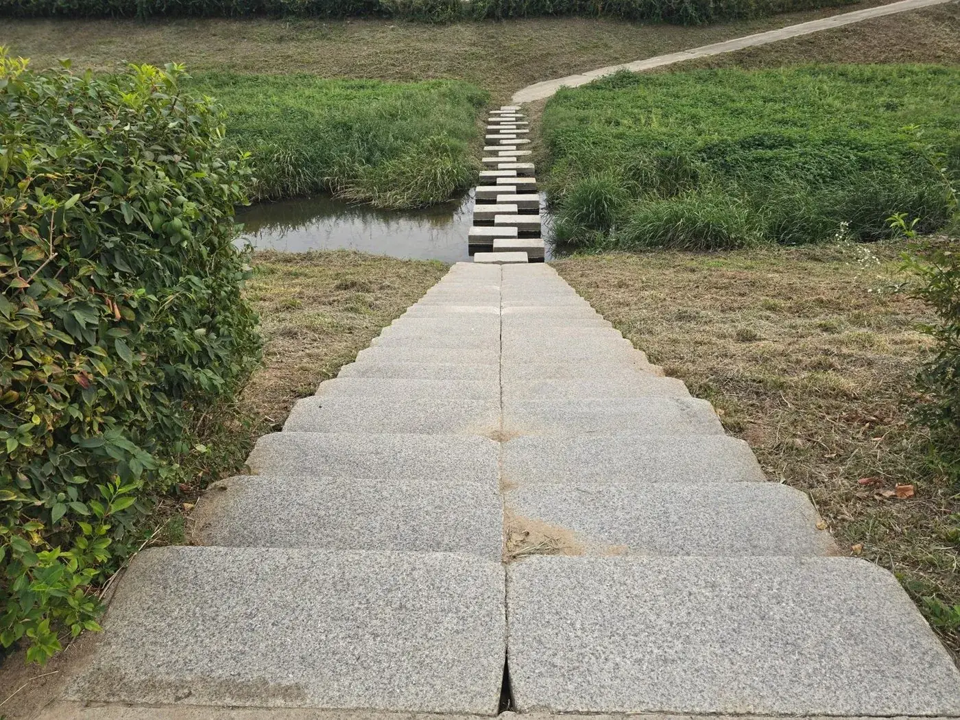 Stepping stones crossing a stream toward a stone stairway